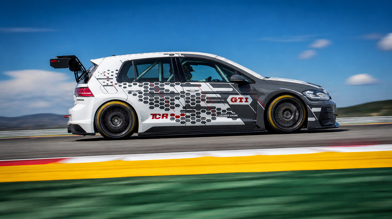 Carro de corrida GTI branco com decalques cinzentos em pista de competição sob céu azul.