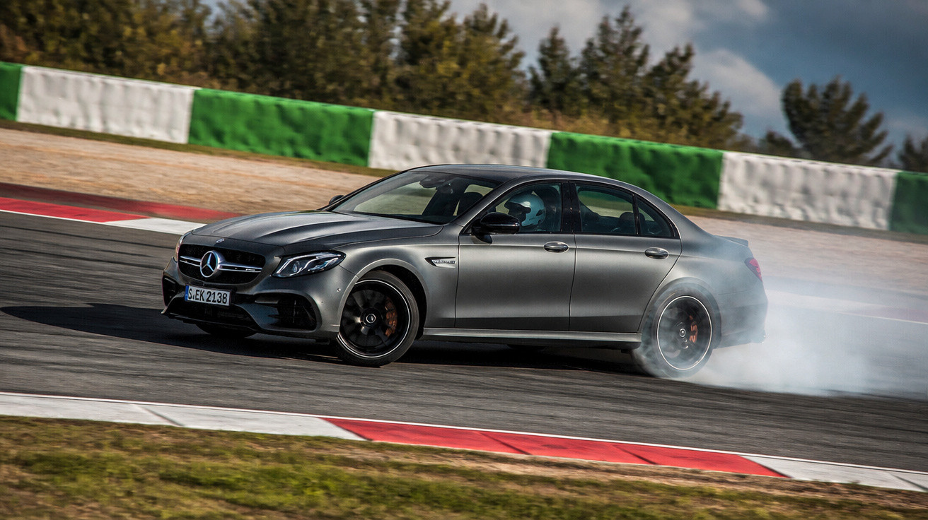 Carro Mercedes cinzento a fazer derrapagens numa pista de corrida com fumo nos pneus.