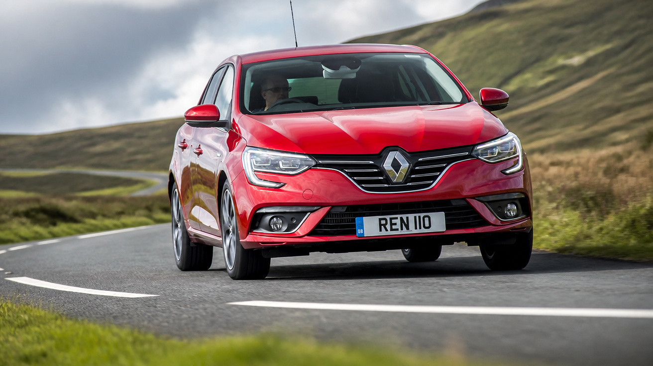 Carro vermelho Renault a circular numa estrada sinuosa em zona rural com colinas ao fundo.